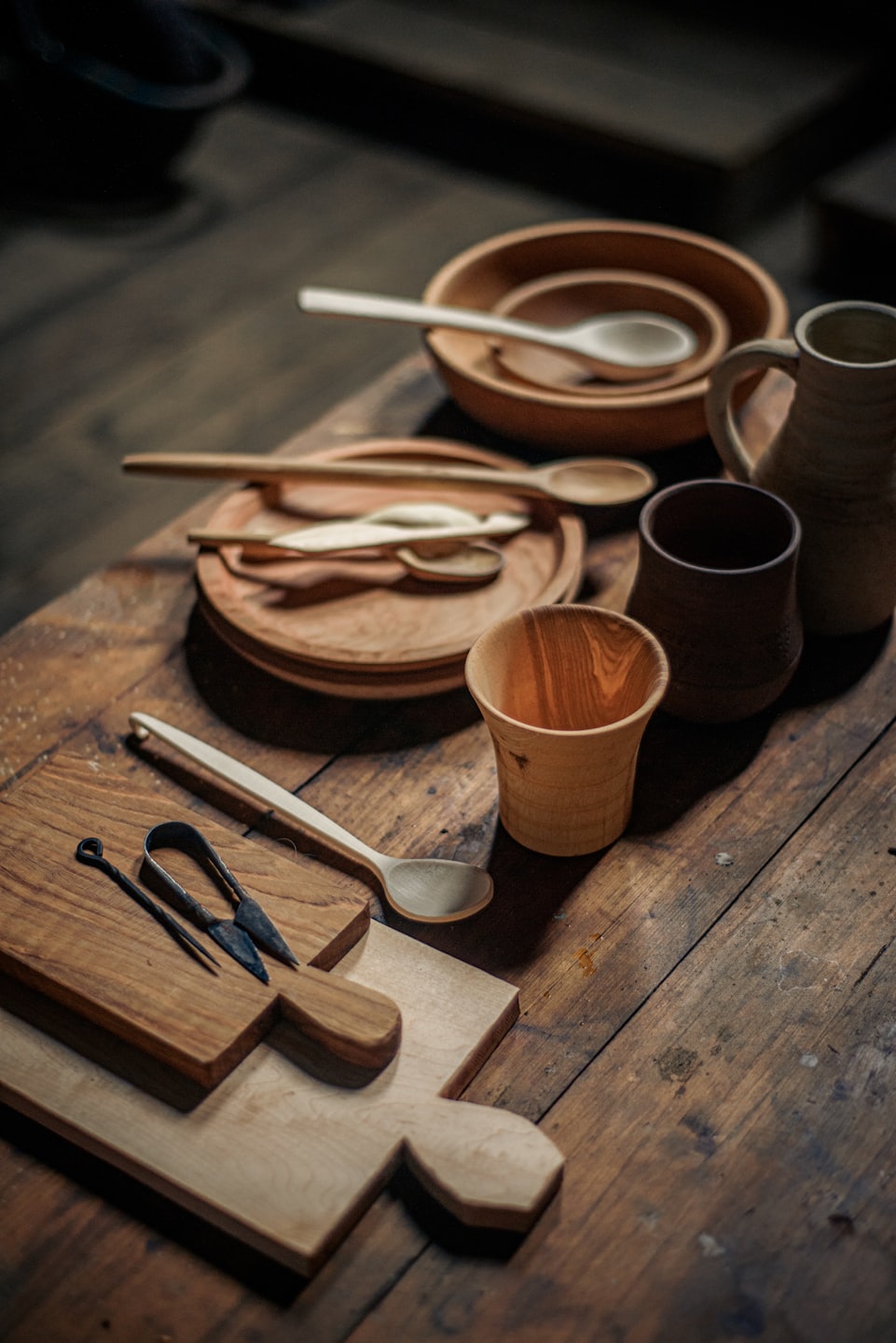 Handcrafted wooden bowls and tools rest on a wooden workbench.